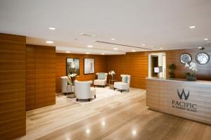 Salón con sala de espera con sillas blancas y recepción en 2 Bedroom Deluxe Beach Apartment Al Marjan, en Ras al Khaimah