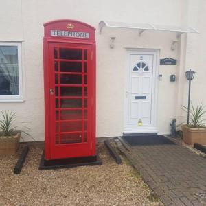 a red telephone booth in front of a house at Stansted Lodge Guest House in Elsenham