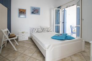 a white bedroom with a bed and a window at Milos Sunset Home in Tripiti