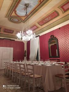 une salle à manger avec une grande table, des chaises et un lustre dans l'établissement Palazzo Introna, à Mola di Bari