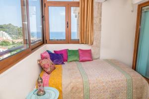 a bedroom with a bed with colorful pillows and a window at Apartment Elena Petrovac in Petrovac na Moru
