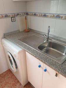 uma cozinha com um lavatório e uma máquina de lavar roupa em La Casita Blanca - Vistabella Golf em Orihuela