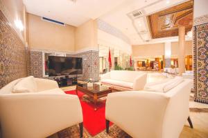 ein Wohnzimmer mit weißen Stühlen und einem Flachbild-TV in der Unterkunft Hotel Menzeh Dalia in Meknès