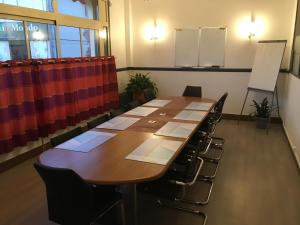 une salle de conférence avec une grande table et des chaises dans l'établissement Hotel le Rallye, à Soissons