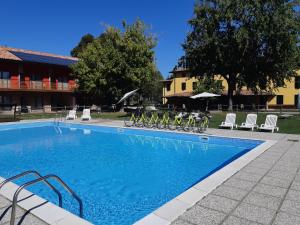 a swimming pool with chairs and bikes next to a building at Agriturismo ai Due Leoni in Aquiléia