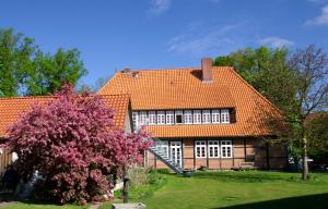 una casa con techo naranja y un árbol en Hotel TraumzeitHof, en Eschede