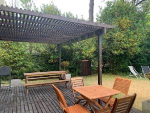 a wooden picnic table and chairs under a pergola at Silenios in Pinamar