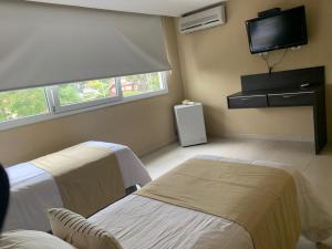 a room with two beds and a flat screen tv at Silenios in Pinamar
