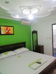 1 dormitorio con cama blanca y pared verde en Hotel Mansión del Cesar, en Aguachica