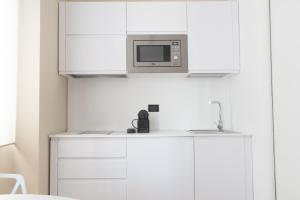 uma cozinha com armários brancos e um micro-ondas em Redi Suite em Bari
