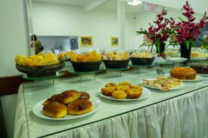 a table topped with plates of pastries and other foods at Pousada Paraiso in Guanambi