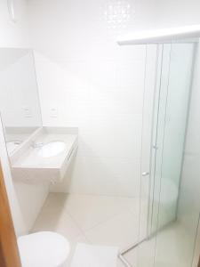 a white bathroom with a sink and a toilet at Hotel Colorado in Aparecida