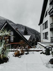 a house with snow on the ground next to a building at Неотель in Krasnaya Polyana