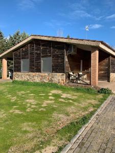 uma casa de madeira com um alpendre e um pátio em Hostal - Bungalows Camping Cáceres em Cáceres