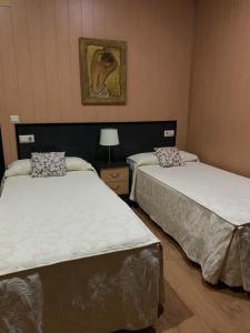 a room with two beds and a lamp in it at Hostal - Bungalows Camping Cáceres in Cáceres