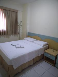 a bedroom with a bed with white sheets and a window at Condomínio Flat La Perla in Fortaleza
