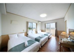 ein Hotelzimmer mit 2 Betten, einem Schreibtisch und Fenstern in der Unterkunft Green Garden Hills 3F-1 - Vacation STAY 15233v in Okinawa
