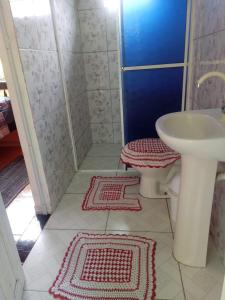 a bathroom with a sink and a toilet and two rugs at Pousada Serena Superagui in Superagui