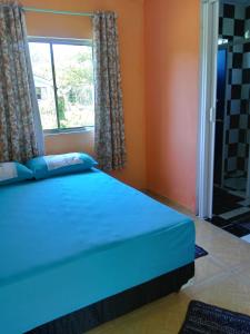 Cama azul en habitación con ventana en Pousada Serena Superagui en Superagui