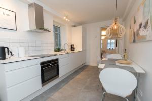 a kitchen with white cabinets and a table and chairs at Harbour Walk in Sønderborg