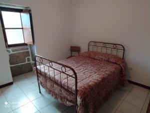 1 dormitorio con 1 cama con edredón rojo y ventana en Casa Prado de Mó, en Arcos de Valdevez