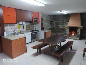 a kitchen with a wooden table and a fireplace at Casa Prado de Mó in Arcos de Valdevez