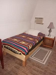 Bett in einem Zimmer mit einem Tisch und einer Lampe in der Unterkunft Cabañas Rústicas El Benny by Rotamundos in Loreto
