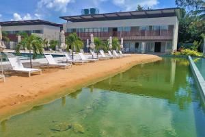 een rij stoelen op een strand naast een hotel bij Qavi - Flat completo com piscina privativa #ÎledePipa in Pipa