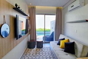 een woonkamer met een bank en een groot raam bij Qavi - Flat completo com piscina privativa #ÎledePipa in Pipa
