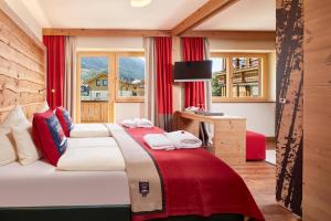 a bedroom with two beds with red curtains and a window at Hotel Hasenauer in Saalbach-Hinterglemm