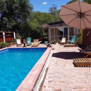 a swimming pool with chairs and an umbrella at Los Arboles in Villa Urquiza