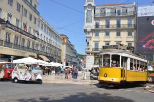 a yellow trolley car on a city street with buildings at Apartamento Chiado Carmo 53 in Lisbon