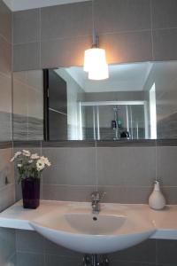 lavabo con espejo y jarrón de flores en Aba Sea House en Balatonszárszó