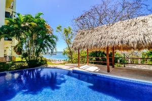 a resort swimming pool with a thatch roof at Oceanica 804 in Playa Flamingo