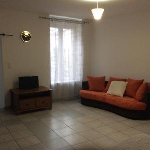 sala de estar con sofá naranja y TV en Studio confortable 33 m2, en Hérépian
