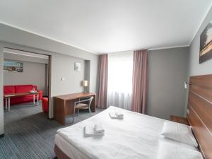 Hotel Tychy في تيخي: غرفة في الفندق مع سرير ومكتب
