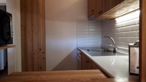 a small kitchen with a sink and a microwave at Apartment 24 Hotel Etrier pool & spa in Crans-Montana