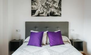 1 dormitorio con 1 cama con almohadas moradas en Apartamento MyM2 en Gijón