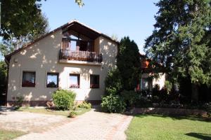 een wit huis met een balkon en een tuin bij Aba Wellness House in Balatonszárszó
