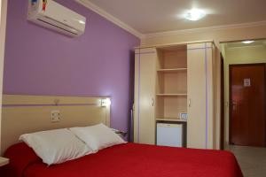 a bedroom with a red bed and purple walls at Bombinhas Praia Apart Hotel - unidade rua Bem Te Vi in Bombinhas