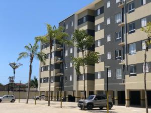a building with palm trees in a parking lot at Apto 2 Dorms, 1 Suíte, JP2 Home Resort Ubatuba - Churrasqueira Gourmet, Ar Condicionado, Piscinas, Sauna e Salão de Jogos in Ubatuba