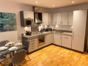 uma cozinha com armários brancos e uma mesa com cadeiras em Urban Living's - The Burley Luxury City Apartment em Oxford