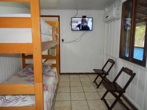 a room with a bunk bed and a tv on the wall at Residencial Brisa da Ilha do Mel in Ilha do Mel
