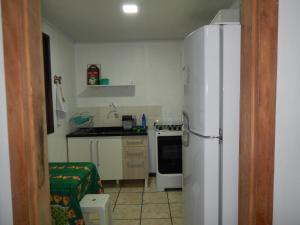 a kitchen with a white refrigerator and a stove at Residencial Brisa da Ilha do Mel in Ilha do Mel