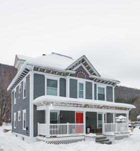 una casa gris con una puerta roja en la nieve en Chateau Lodge - Ski Shandaken, Hunter, Catskills, Windham, Belleayre, en Shandaken