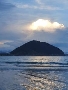 a mountain in the middle of a body of water at Pernambuco Club House in Guarujá
