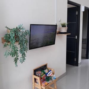 TV de pantalla plana colgada en una pared con una caja de comida en Villa Seruni Bandungan, en Bandungan