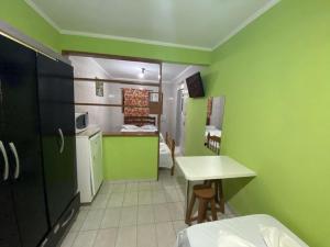 una pequeña cocina con paredes verdes, mesa y sillas en Hotel Mar Casado, en Guarujá