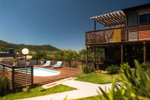 un patio trasero con piscina y sillas y una casa en LAS ROZAS Parador, en Praia do Rosa