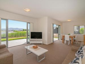 a living room with a couch and a tv and a table at Lakeside Villa Retreat - Matarangi Downstairs Unit in Matarangi